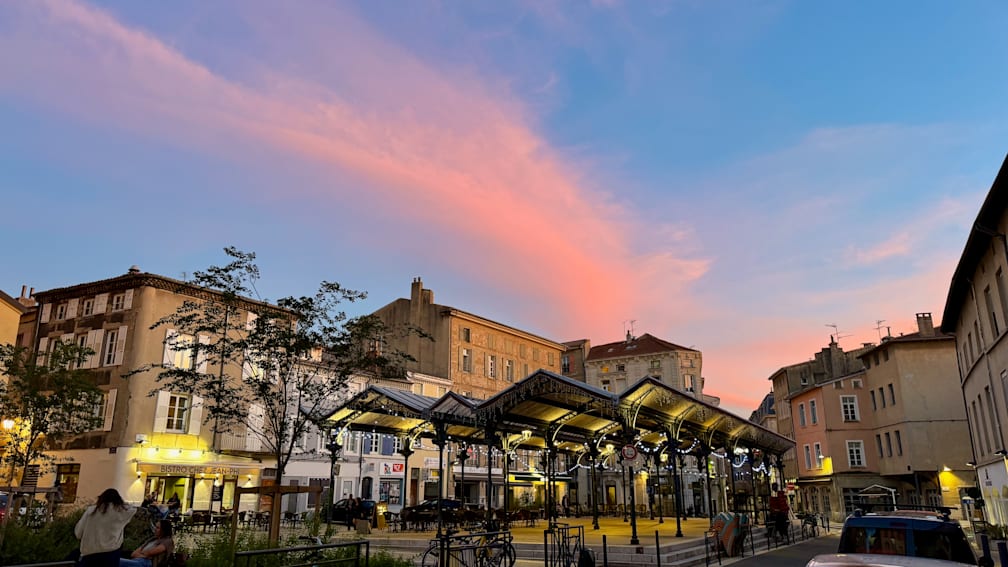 The sky is pink and blue and has many balloons.