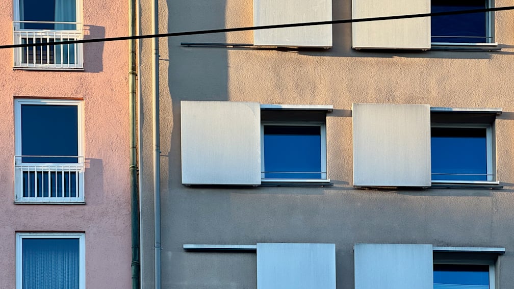 A window on the side of a building with the glass pane showing a blue sky.