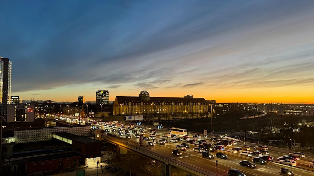 A bridge is shown with cars on it and a large building in the background.