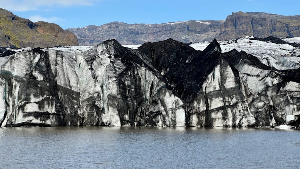 Large block of ice is seen in front of a mountain range.
