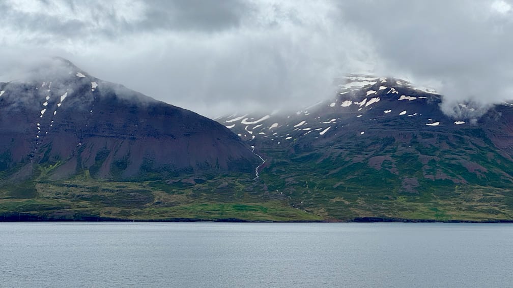 A stream flows down a mountainside and into a lake.