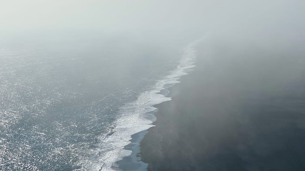 An aerial view of a wetland with waves crashing against the shore.