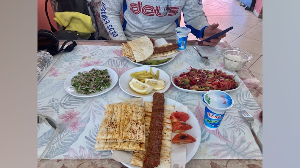 A man sits at a table with plates of food in front of him.