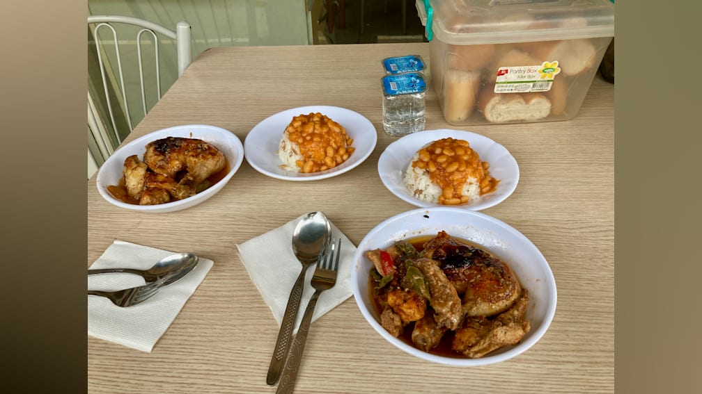 A table with four bowls of food and silverware on it.