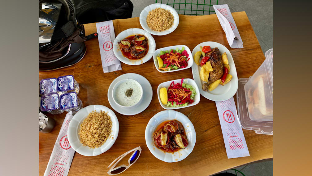 A table with many different foods on it and a couple of forks and knives on the side.