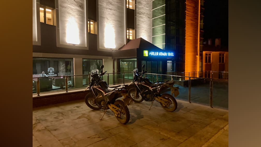 Two motorcycles are parked in front of a building at night.