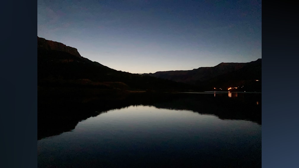 A lake at sunset with trees in the background.