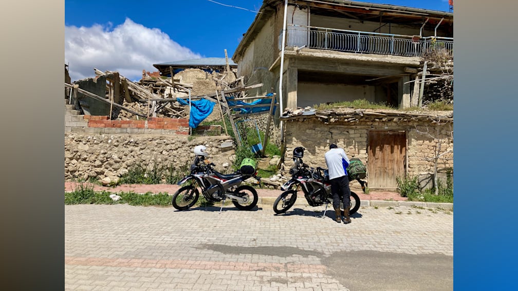 A man is standing next to his motorcycle on the street.