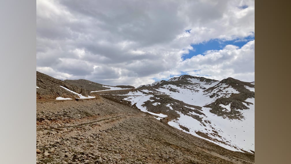 A road winds its way up a mountain covered in snow.