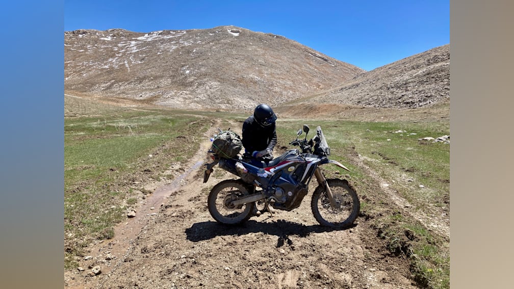 A man is sitting on his motorcycle in the middle of a field.