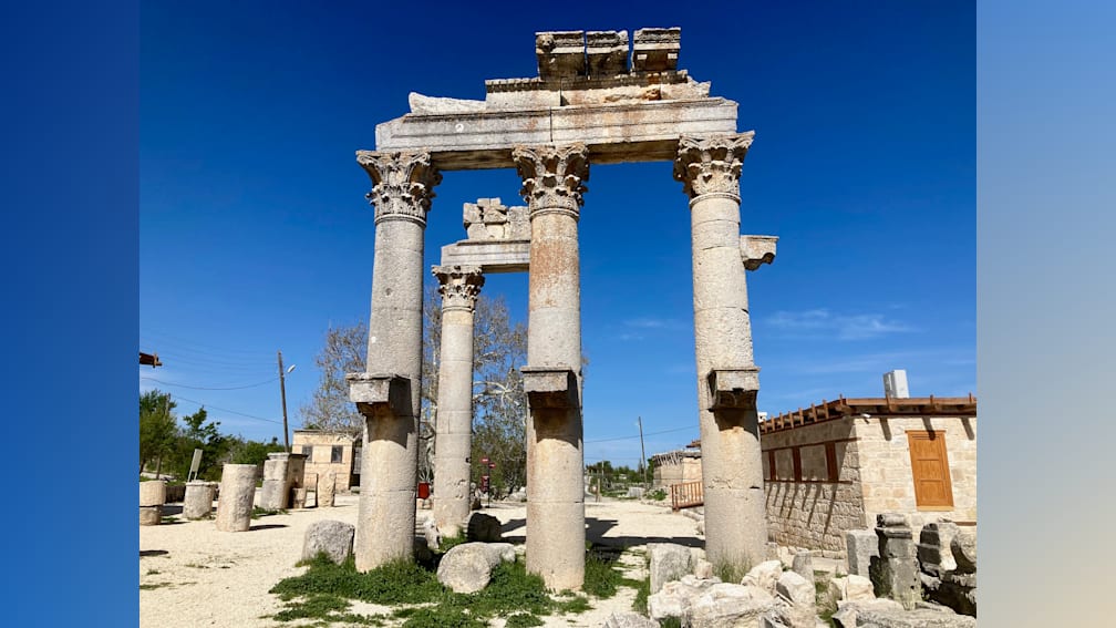 Four large columns with stone tops that are weathered and missing pieces of stone.