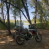 A person is taking a picture of a motorcycle parked next to a lake.