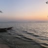 A boat is floating on a body of water with the sun setting in the background.