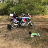 A person is leaning on a motorcycle in a field.