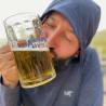 A man drinking from a large glass with the words Alligator Brand on it.