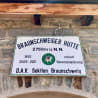 A sign written inGerman is displayed on a stone wall.