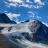A large snow covered mountain with a plane flying overhead.