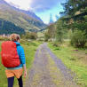 A woman wearing a blue jacket is walking down a path in the woods.