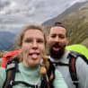 A woman with glasses and a man with a beard on a mountain.