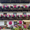 The balcony of a large house is decorated with flowers in hanging baskets.