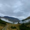 A road winds through a forest of mountains with a lot of misty mountains in the background.