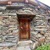 A stone building with a wooden door and a cross on the door.