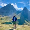 A man wearing a hat stands on a mountain top.