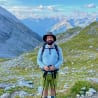 A man standing on a mountain with his hiking poles and a backpack.