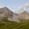 A mountain with a path going up and a field with grass.