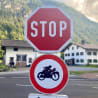 Stop sign on the side of the road that is in front of a white building.