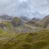 A foggy mountain peak with a grassy slope underneath.