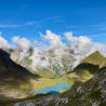 A mountain lake with a blue water and clouds in the background.