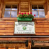 A sign that says "Rffselsehutte" on the side of a building with flowers in a planter next to it.