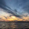 The ocean has a beautiful sunset and the sky is filled with clouds.