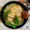 A noodle dish with vegetables such as spinach and onions served in a bowl.