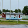 A blue car is parked in front of a red garage.