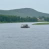A houseboat on a body of water with trees in the background.