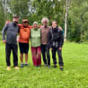 Five people posing for a picture in a field, two of them wearing raincoats.