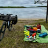 A green and blue blanket has a variety of items on it including a helmet and a bottle of water.