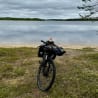 A mountain bike is sitting on the grass next to a body of water.