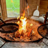 A fire is burning in a grill and cooking some hot dogs while a spatula is nearby to flip them.