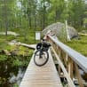 A bicycle is parked on a bridge over water with a sign nearby.