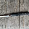 A small, black, blade edge knife lies on a wooden surface.
