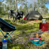 A camping chair and a bicycle are set up in a grassy area next to a tent.
