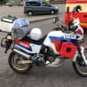 A motorcycle with a red gas tank is parked next to a van.