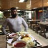 A man stands in front of a table with food on it in a restaurant.