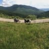 Two motorcycles are parked on a grassy hillside.