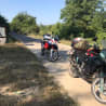 Two motorcycles are parked on a dirt road next to a grassy area.
