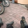 Two people sitting with their feet on a brick sidewalk.