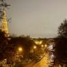 A street view of a city at night with lights on and trees.